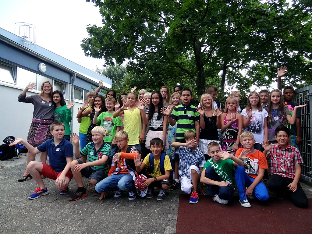 Klassenfoto einer neuen fünften Klasse, einige Kinder strecken die Arme hoch.